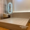 Giường cưới 1m8x2m thiết kế tối giản với đầu cao giường được thiết kế kiêm vách ốp tường, chạy dọc sang không gian để táp đầu giường
