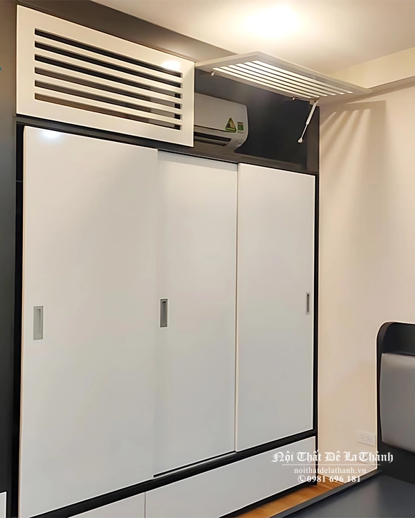Chiếc tủ 2mx2m6 full trần, tầng trên thiết kế các tấm lật piston để che điều hoà, cánh cắt CNC, tầng dưới là cánh lùa màu trắng, thân tủ màu đen