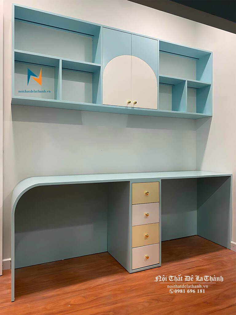 Chiếc bàn học hiện đại thiết kế kèm giá sách treo, một bên đầu bàn được bo cong, phối 2 màu xanh lá và trắng, giữa bàn có trụ 3 ngăn kéo, vừa để các bé cất trữ đồ, vừa là nơi chịu lực cho chiếc bàn học