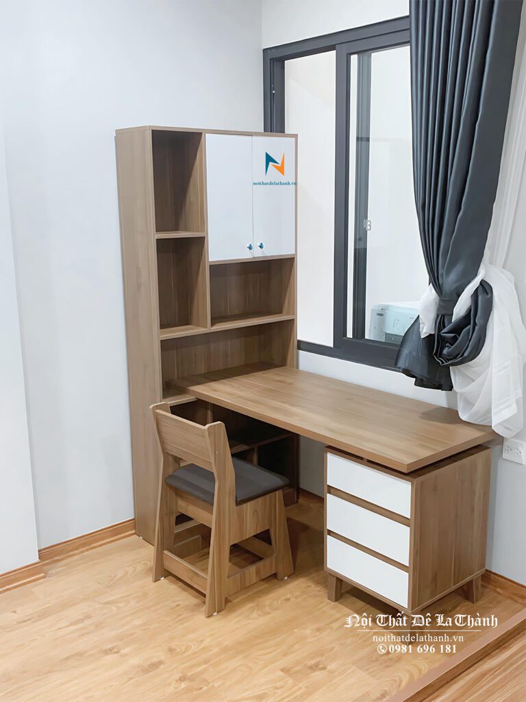 Chiếc bàn gỗ mdf dài 1m2, bên phải là hộc đựng đồ, bên trái là giá sách cao 1m5 dựng đứng từ mặt sàn, phối màu gỗ nâu và màu trắng, dành cho bé trai cấp 1
