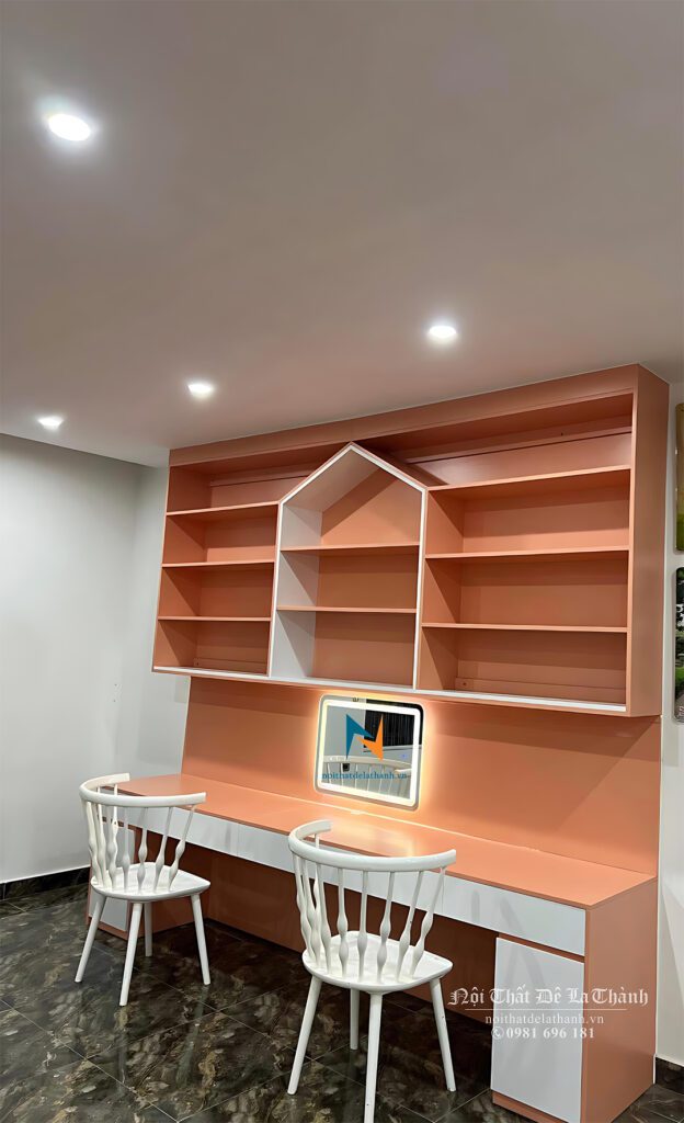 Bàn học thiết kế có kích thước 1m8x2m6 kịch trần, bàn liền giá sách, màu hồng pha màu trắng, ở giữa giá sách thiết kế kiểu mái nhà nhọn, dành cho 2 bé gái cấp 2