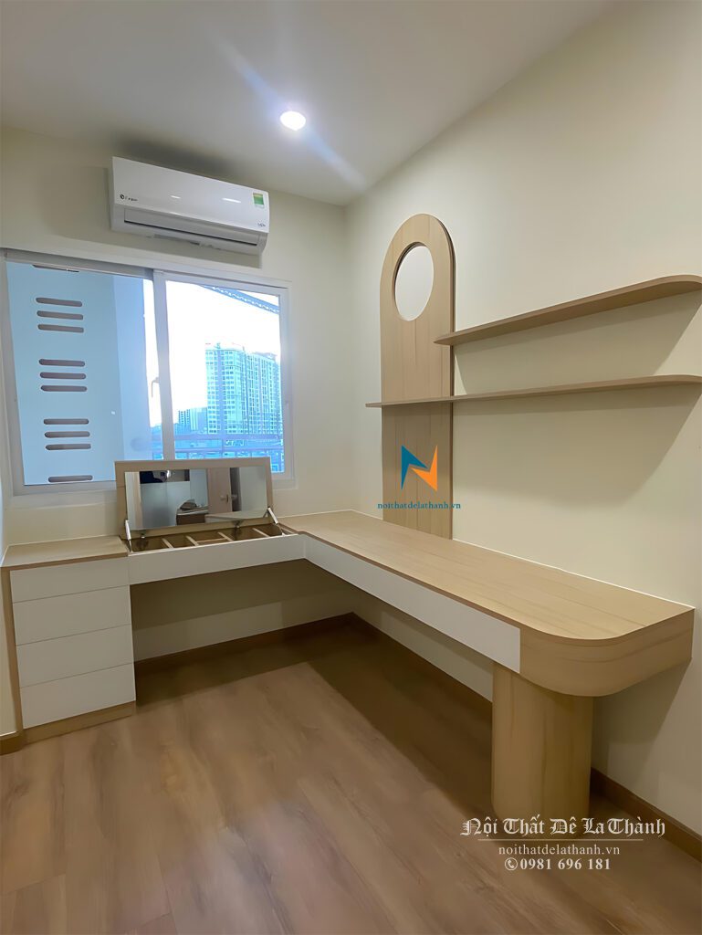 Chiếc bàn học cho sinh viên nữ thiết kế tại chung cư, vế trái dài 1m có tủ đựng đồ và gương trang điểm lật, vế phải dài 1m2, chân trụ tròn, bên trên là giá sách cấu tạo từ 2 chiếc đợt treo bắn vào tường, màu gỗ pha màu cánh trắng
