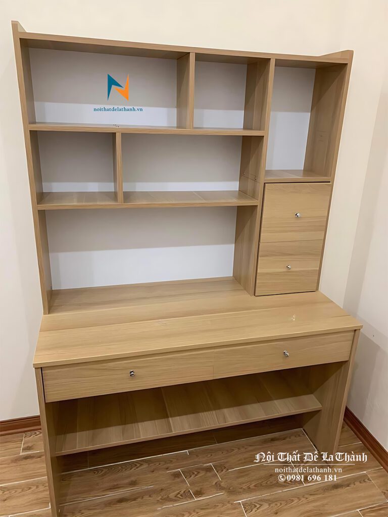 Bàn học liền giá sách 1mx1m95, màu gỗ nâu nhạt, dưới gầm bàn có 1 chiếc giá nhỏ để thêm đồ, trên giá sách phía bên phải có 1 ô với 1 cánh nhỏ đề đồ nhỏ cho các bé