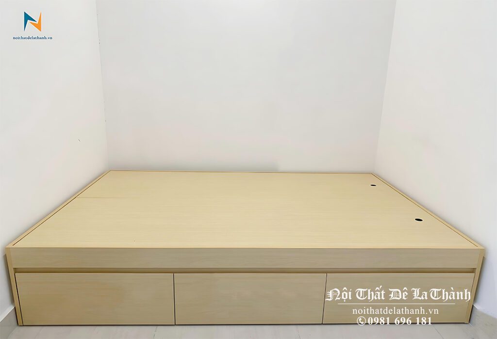 Chiếc giường bệt có 3 ngăn kéo, kích thước 1m6x2m, không đầu cao, màu gỗ vàng nhạt